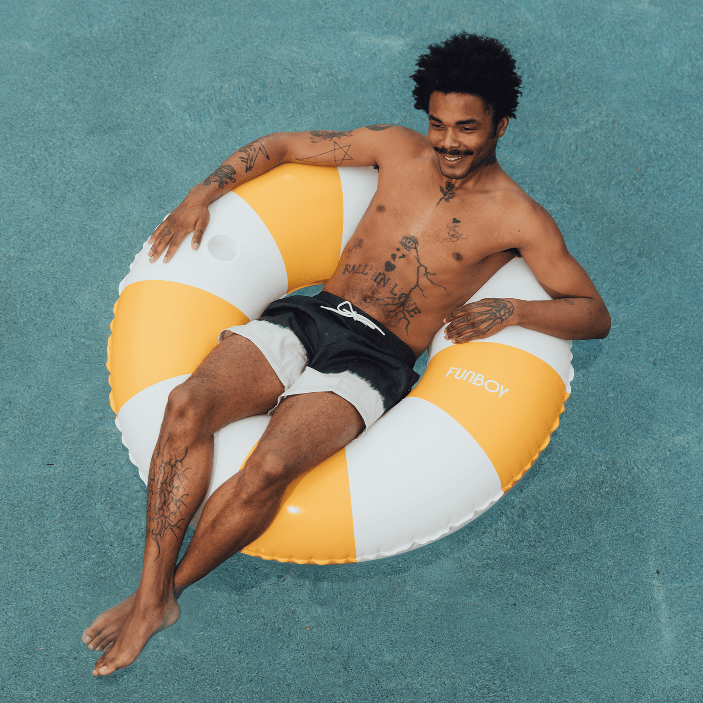 Guy sitting on a Mustard Orange Vintage Tube Float